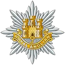 Royal Anglian cap badge: the gold Castle and Key on a silver eight-pointed star, over a title scroll.